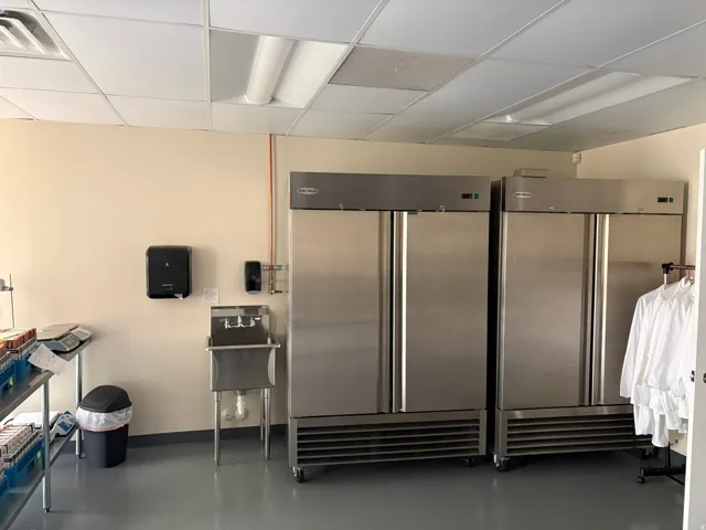 Commercial space featuring two stainless steel industrial refrigerators, a stainless steel utility sink, and durable gray flooring