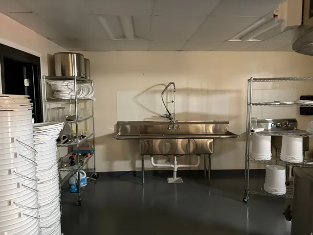 Commercial-grade stainless steel three-compartment sink with integrated sprayer