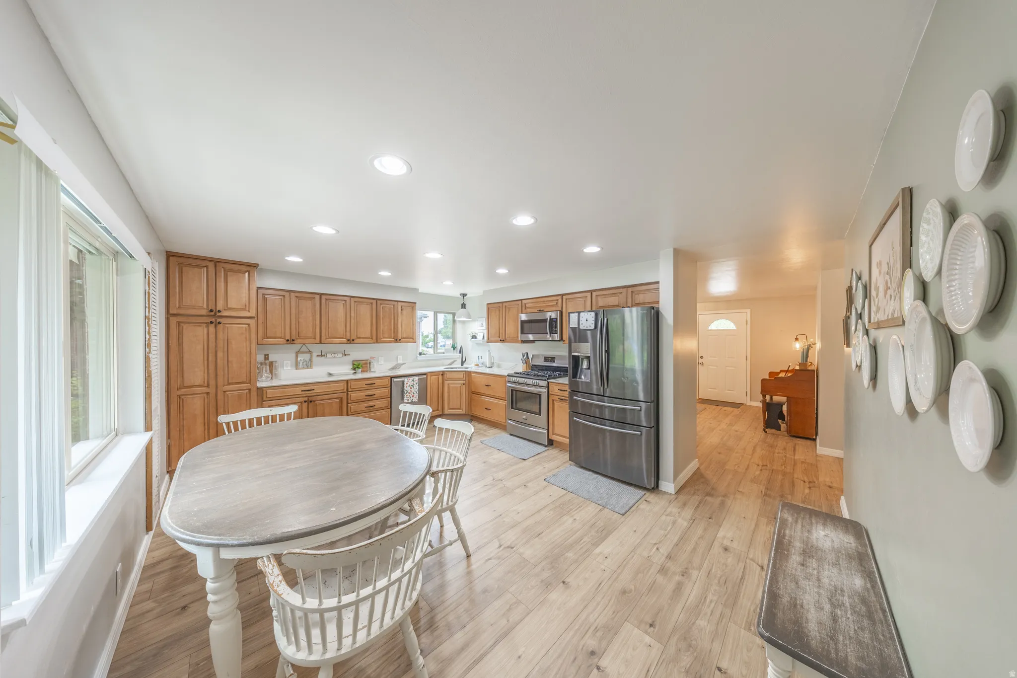 Open-concept kitchen and dining area featuring wood-finish flooring, recessed lighting, wood cabinetry, and stainless steel appliances