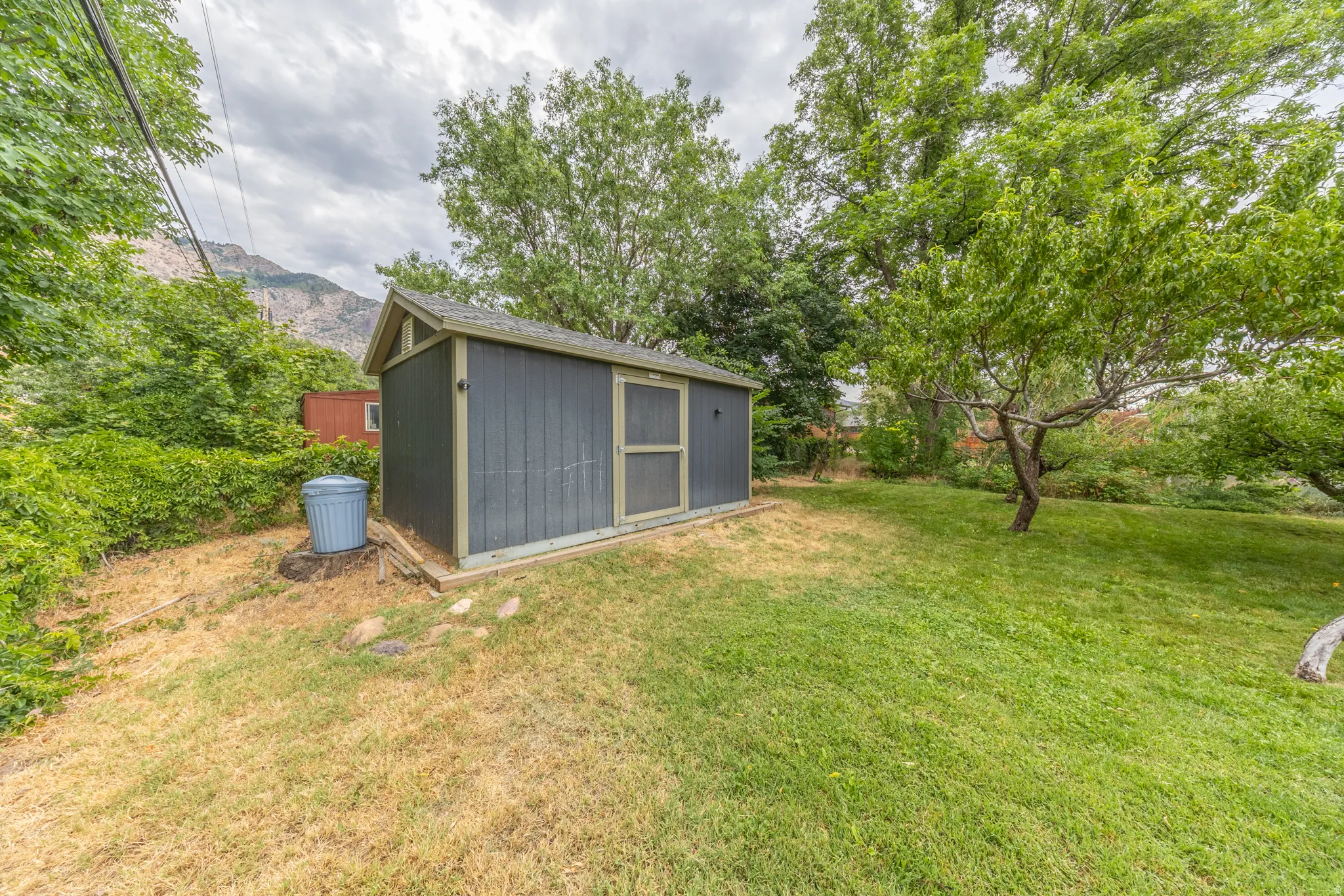 Detached outdoor shed with a gabled roof and a screen door, set on a raised concrete foundation