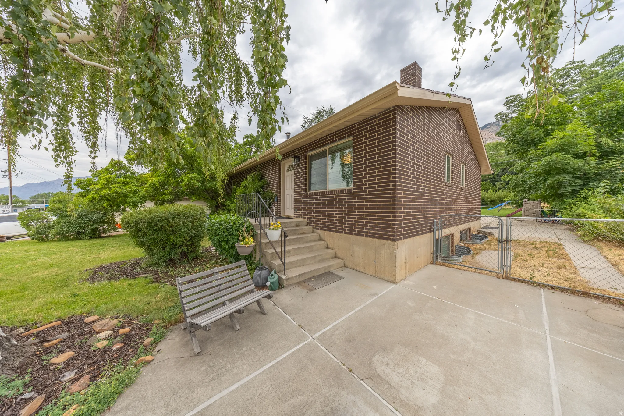 Brick exterior residence featuring a front entry with concrete steps and a metal handrail