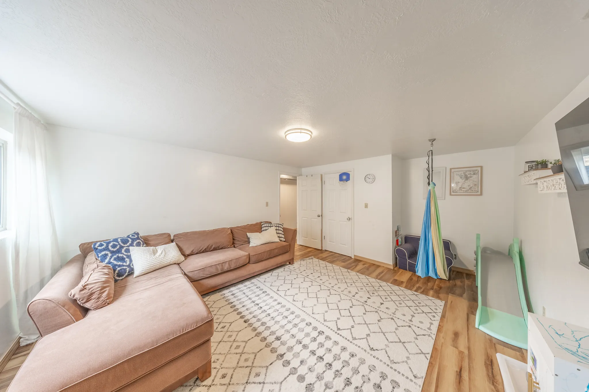 Spacious room featuring wood-finish flooring, white walls, and a ceiling light fixture