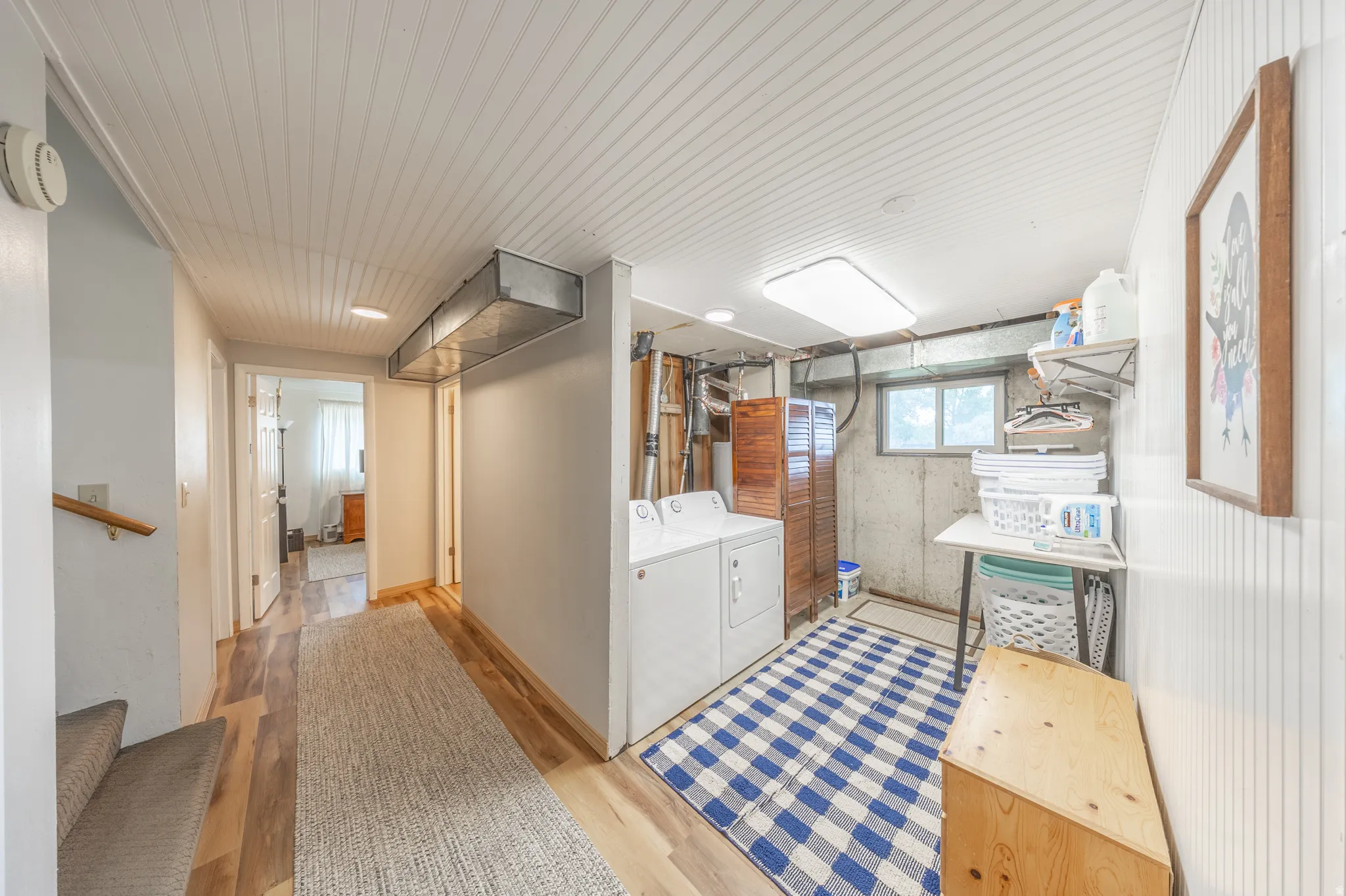 Dedicated laundry area featuring white appliances, a window, and wood-finish flooring