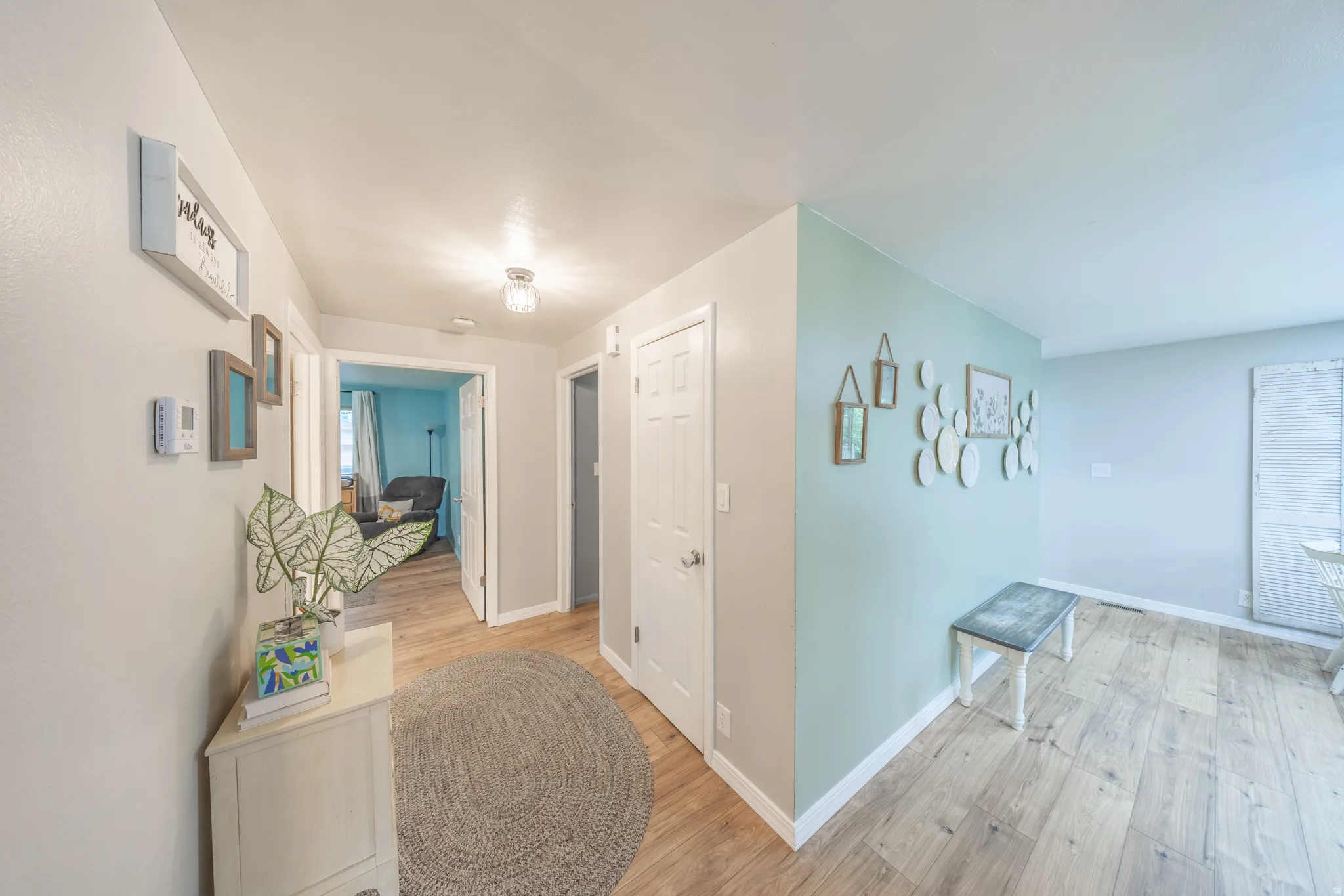 Bright interior space featuring light wood-finish flooring, white baseboards, and a combination of light gray and soft blue wall colors