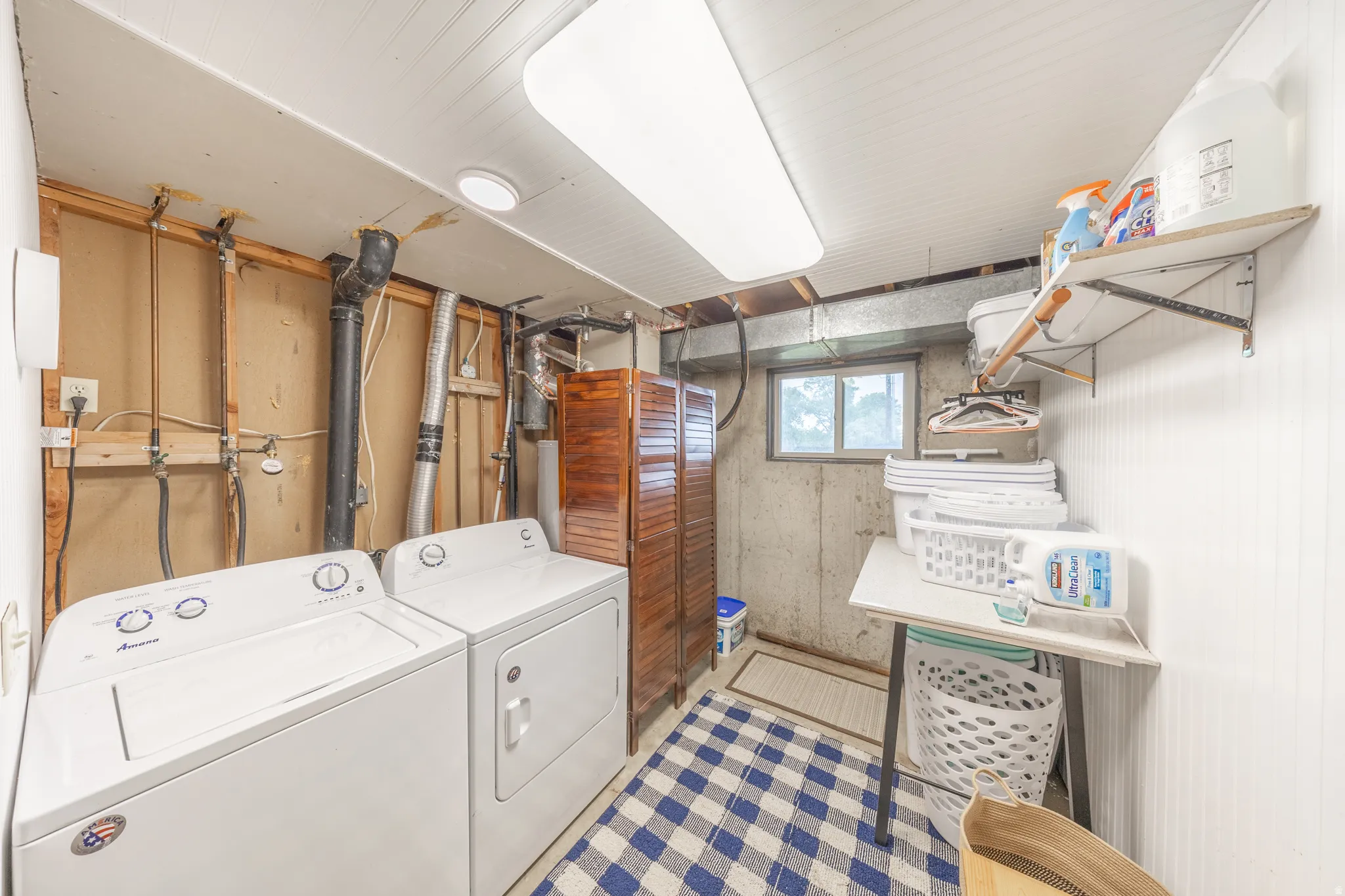 Dedicated utility area featuring a washer and dryer, concrete foundation wall, and a window for natural light