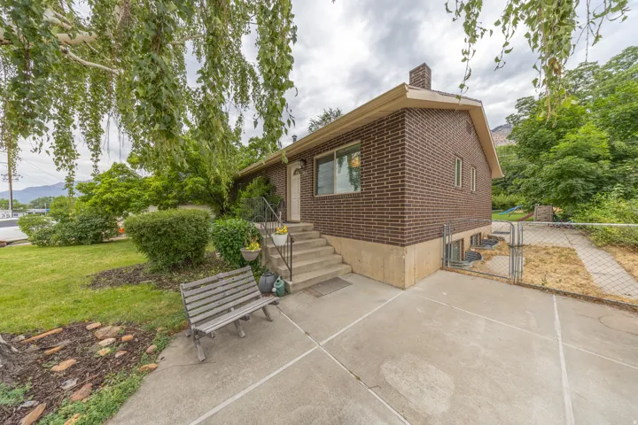 Brick exterior residence featuring a front entry with concrete steps and a metal handrail
