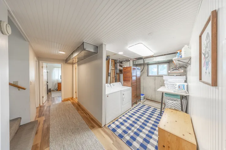 Dedicated laundry area featuring white appliances, a window, and wood-finish flooring