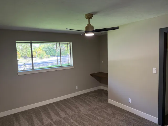 Room featuring light gray walls, white baseboards, and patterned carpet flooring