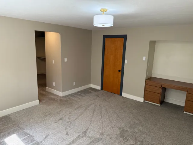 Spacious room featuring gray carpet, light tan walls, and white baseboards