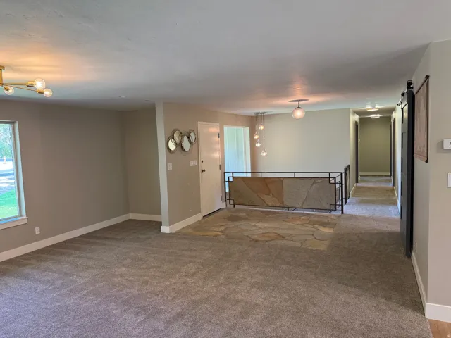 Spacious carpeted area with a modern gold-finish chandelier