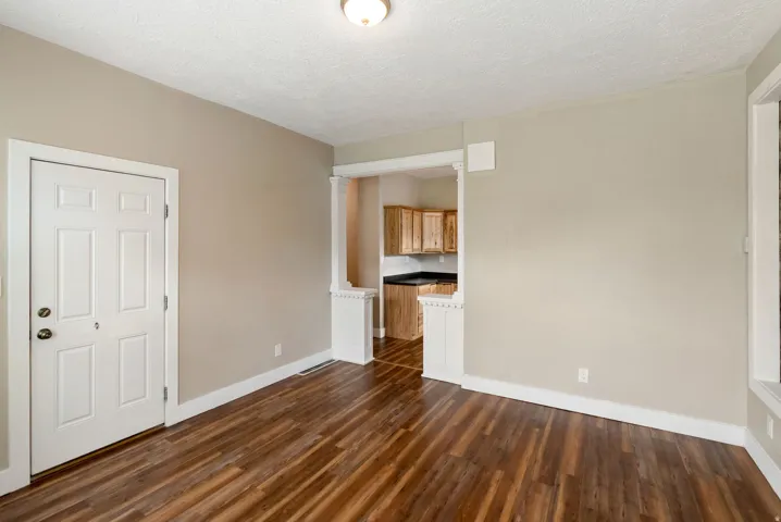 East unit. Spacious room featuring wood-finish flooring, neutral-toned walls, and white trim