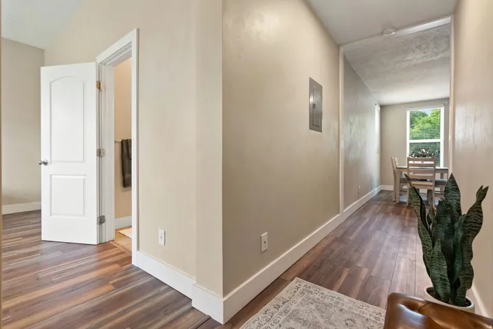 West unit. Hallway featuring wood-finish flooring, light neutral wall paint, and white trim