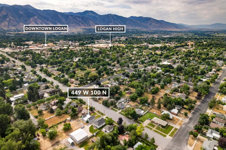 Aerial perspective showcasing a residential area with mature trees and mountain backdrops