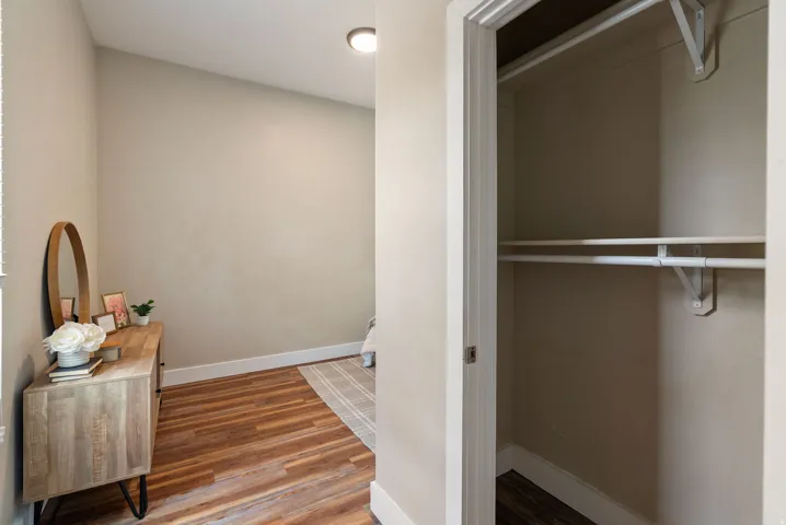 West unit. Bedroom area featuring wood-finish flooring, light-toned wall paint, white baseboards, and a recessed ceiling light