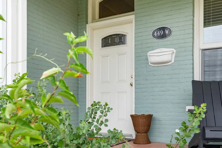 Entrance to the West unit. Painted brick exterior featuring a contrasting white entry door with an arched window insert