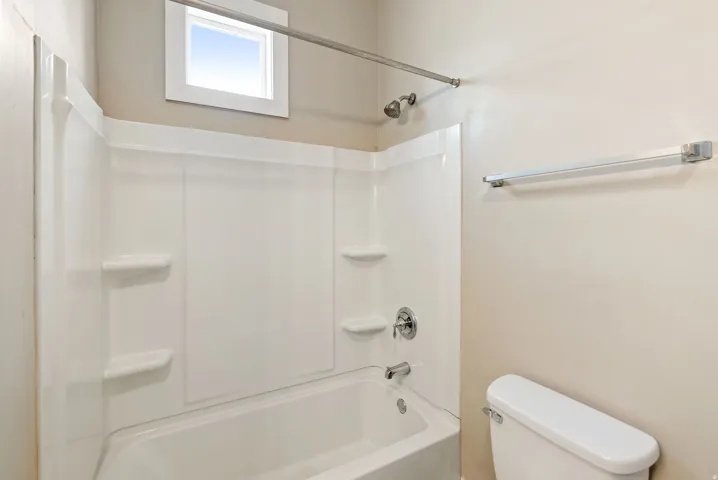 East unit. White tub and shower combination with integrated shelving
