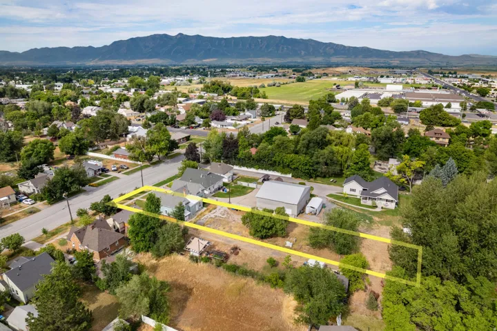 Aerial perspective of a property with surrounding residential structures and mature trees