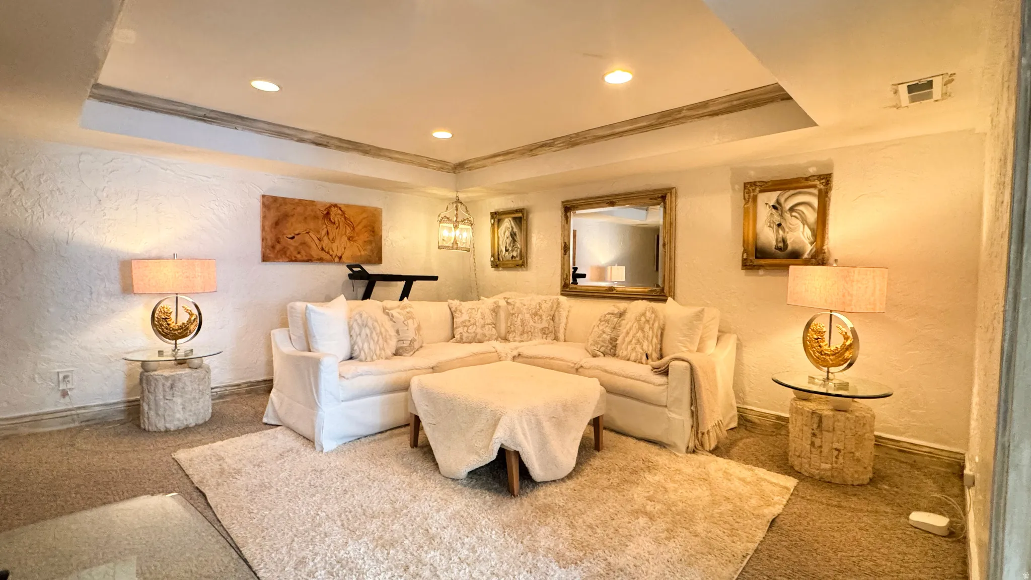 Recessed lighting illuminates a spacious room featuring textured white walls and contrasting ceiling details