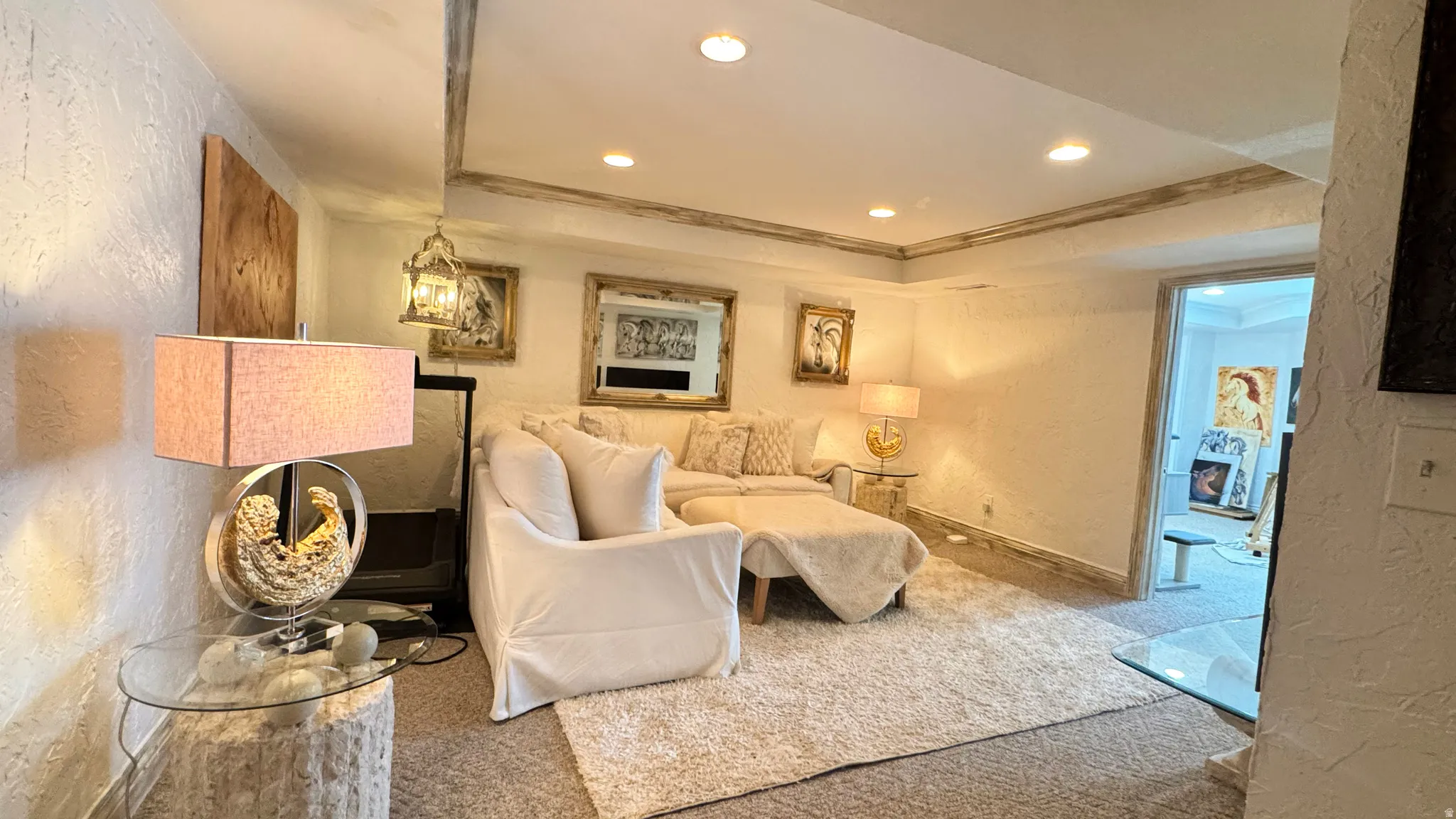 Recessed lighting illuminates this room, featuring textured white walls and a light-toned, plush carpet