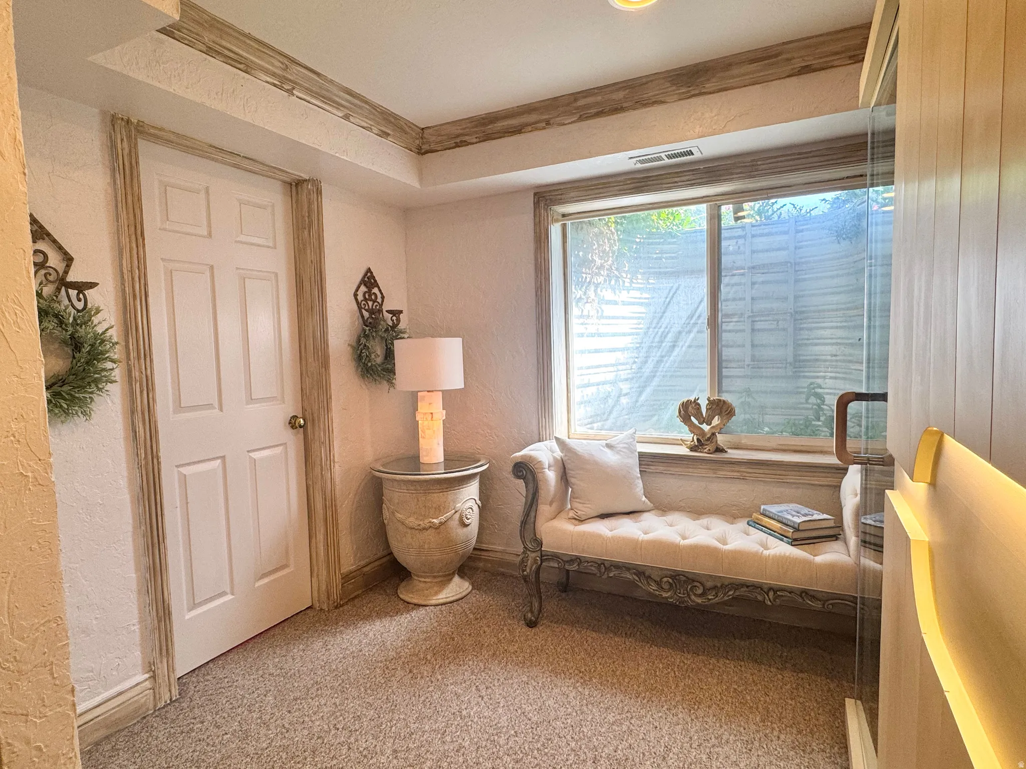 Carpeted floor with a window, white panel door, and decorative trim details