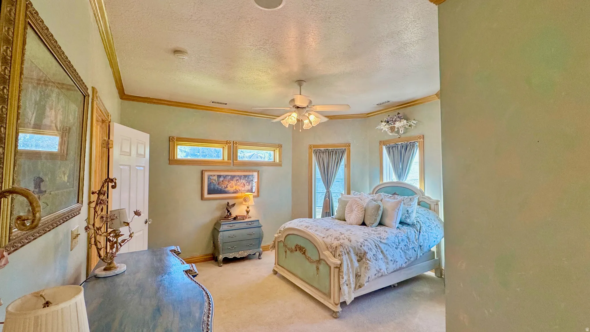Recessed lighting and a ceiling fan fixture highlight a room featuring a paneled door, three transom windows, and two full-height windows with architectural trim