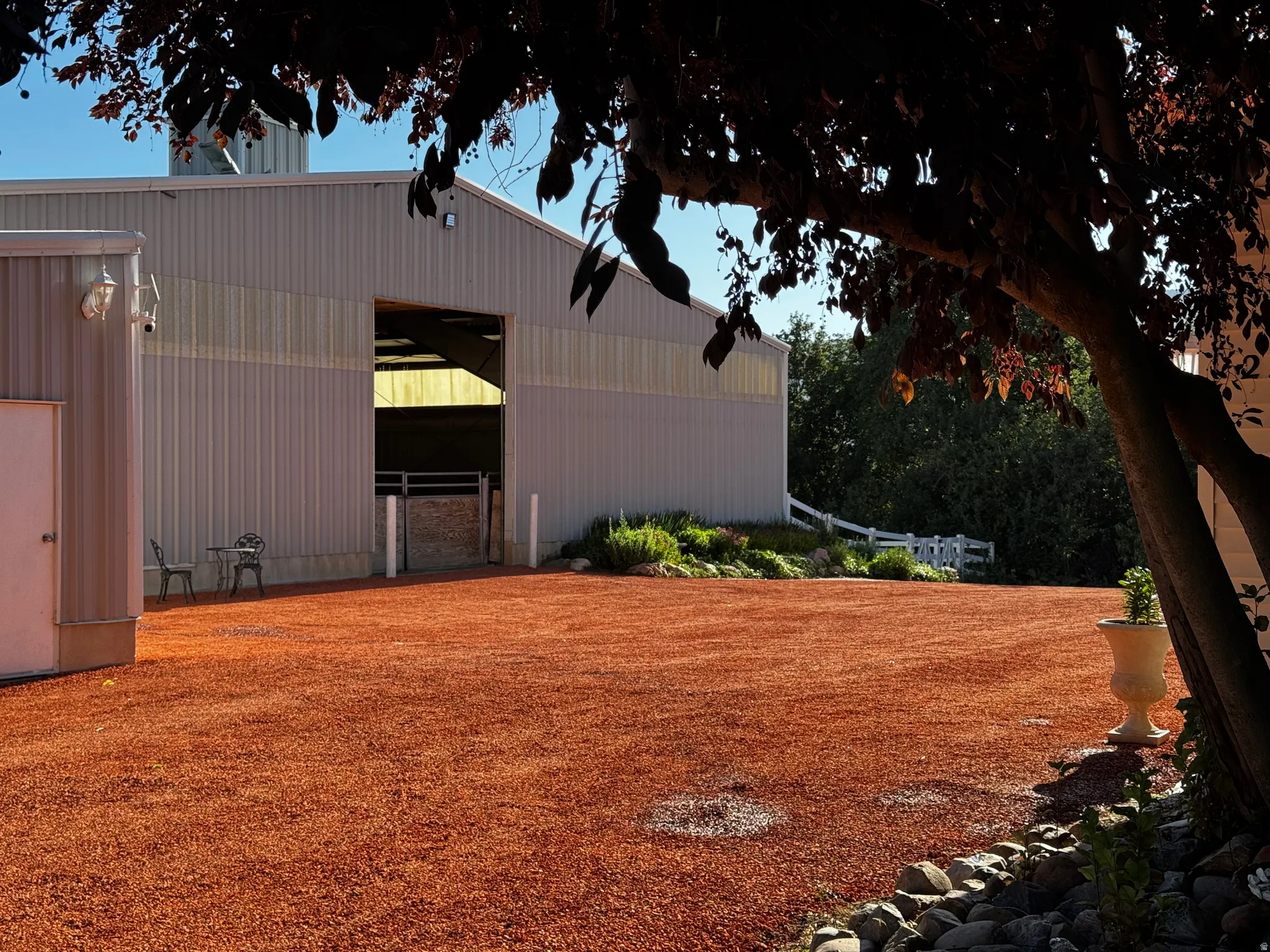 Expansive red gravel area fronting a large utility building with a prominent open bay entrance