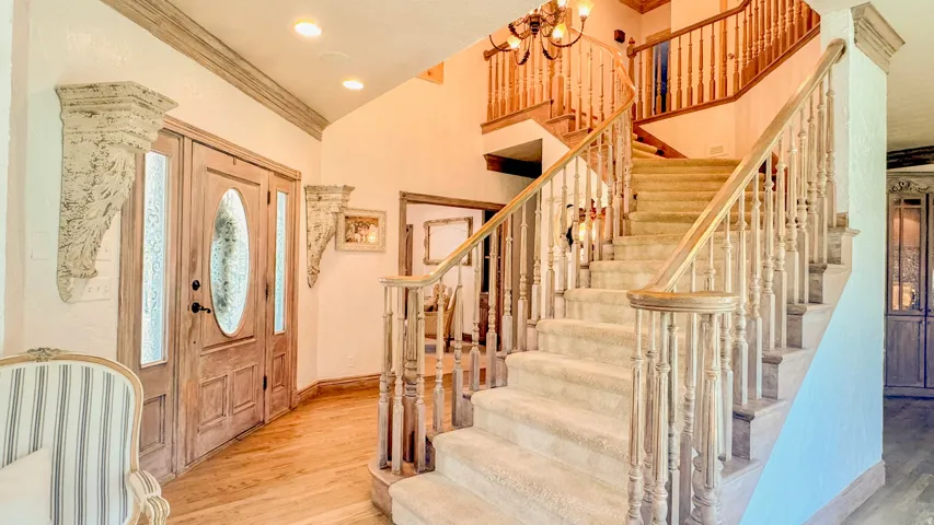 Gracious entry featuring a grand staircase with wood balusters, carpeted treads, and a wood handrail
