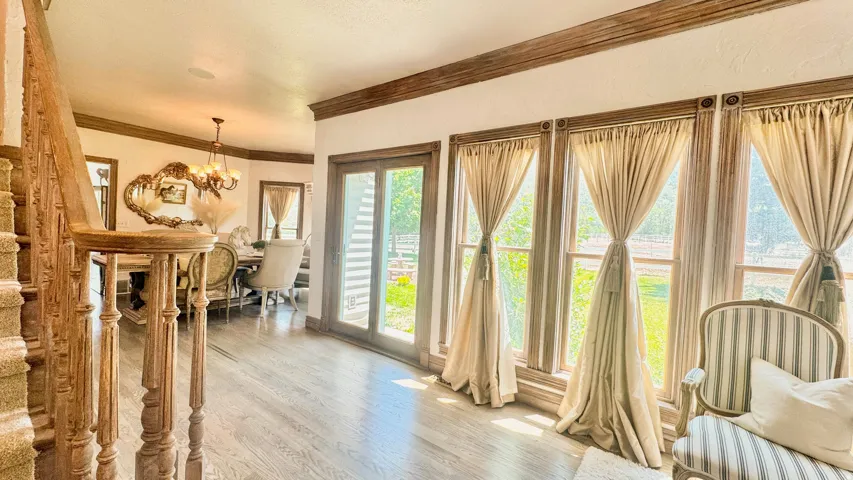 Spacious foyer featuring wood-finish flooring, an ornate carved wood staircase, and extensive window treatments