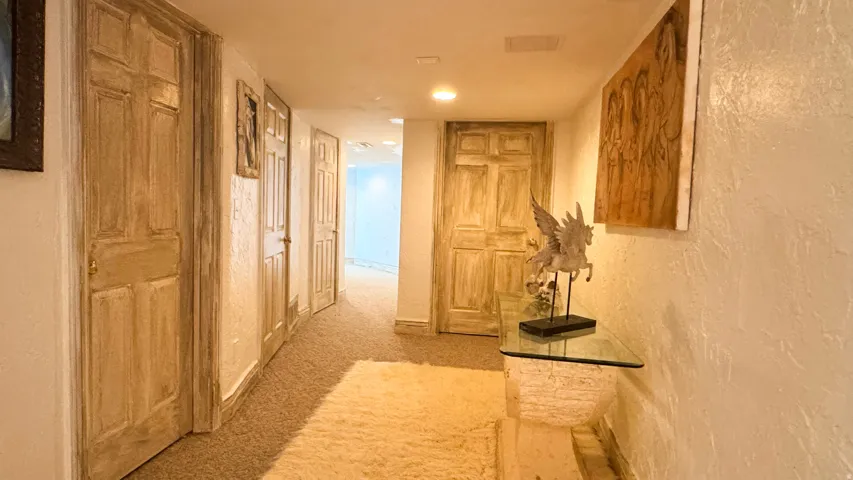 Hallway featuring textured walls, recessed lighting, and carpet flooring