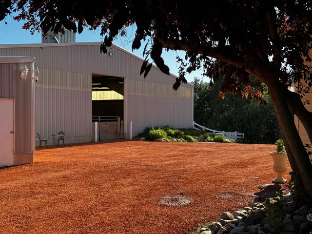 Expansive red gravel area fronting a large utility building with a prominent open bay entrance