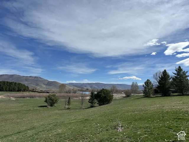 Expansive green lawn sloping towards a body of water, bordered by distant mountains