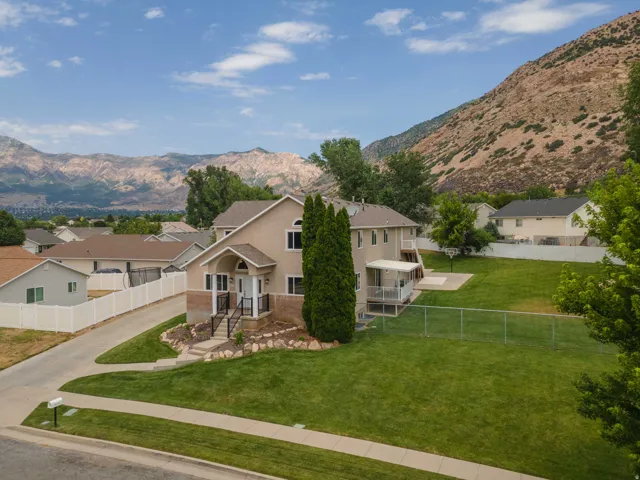 Exterior residence featuring a covered porch entry, a large backyard with a patio, and mountain scenery