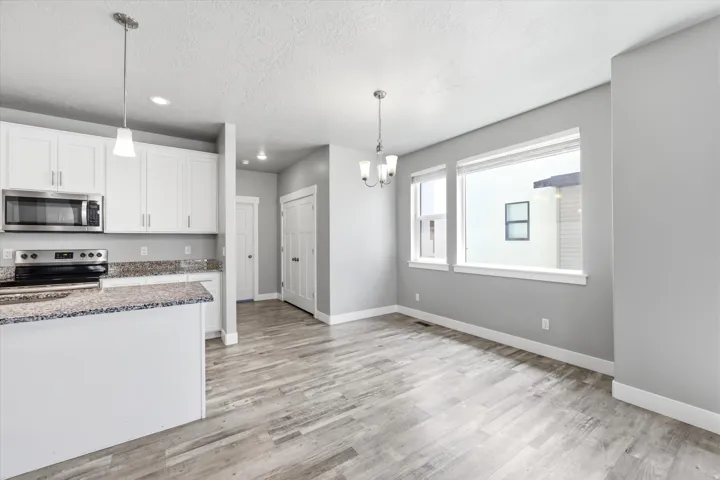 Kitchen featuring white cabinetry, stainless steel appliances, and a peninsula with a stone-finish countertop