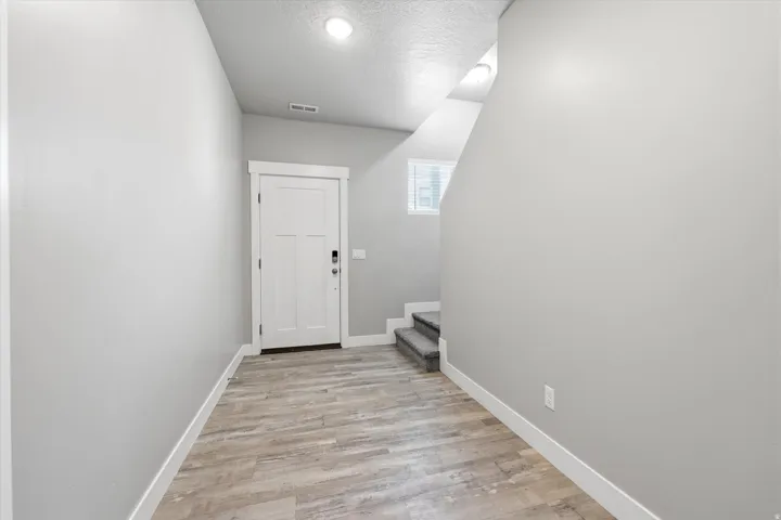 Entryway featuring wood-finish flooring, a contemporary paneled door, light gray walls, white baseboards, and overhead recessed lighting