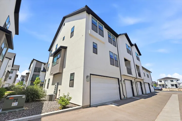 Contemporary townhome exterior featuring white stucco siding and black trim accents