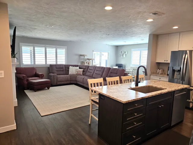 Open-concept living space with dark wood-finish flooring, recessed lighting, and white plantation shutters