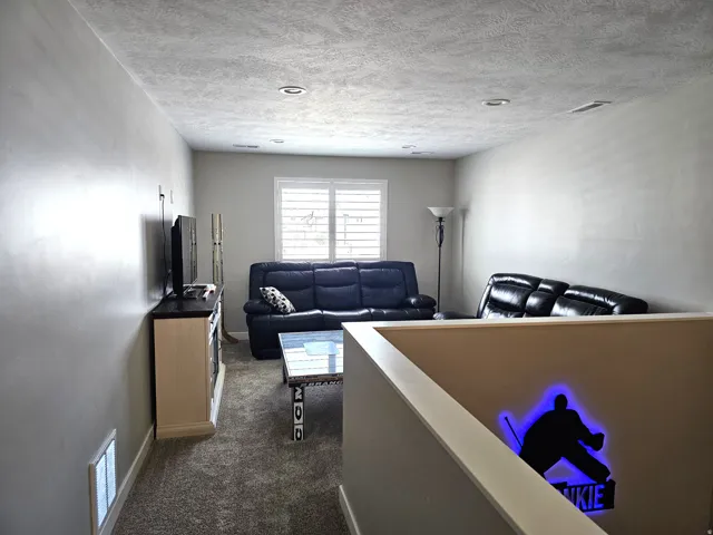 Carpeted recreation area featuring recessed lighting and a window with white louvered shutters
