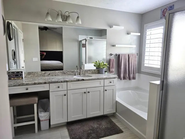 Spacious bathroom featuring a white vanity with granite-style countertop, integrated sink, and an expansive wall mirror