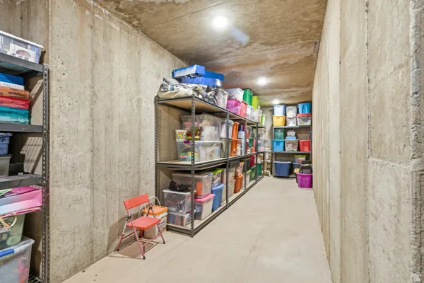 Unfinished basement storage area featuring concrete walls and flooring