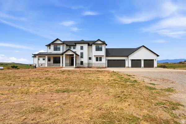Modern farmhouse exterior featuring white vertical siding, black trim, a multi-car garage, covered entry porch, and stone accents
