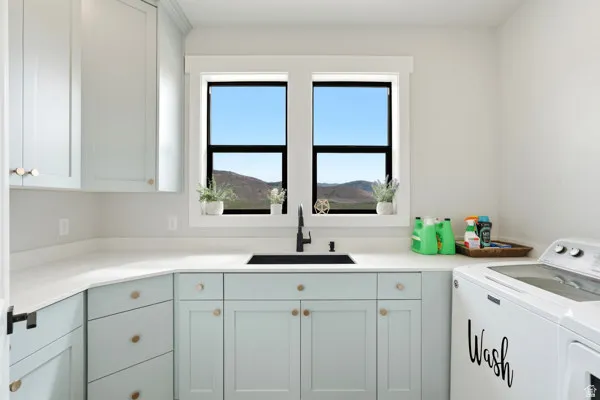Modern laundry space with light blue lower cabinetry and white upper cabinets
