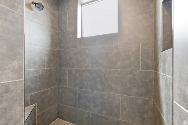 Tiled shower enclosure featuring rectangular gray wall tiles, a built-in shower niche, and a corner bench