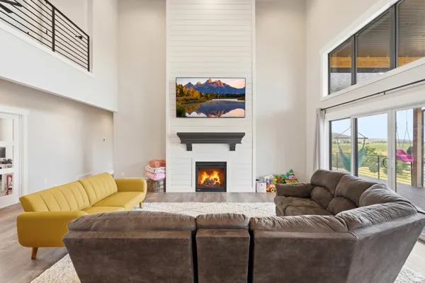 Two-story living area featuring a tall fireplace with a shiplap surround, a dark mantel, and an electric insert
