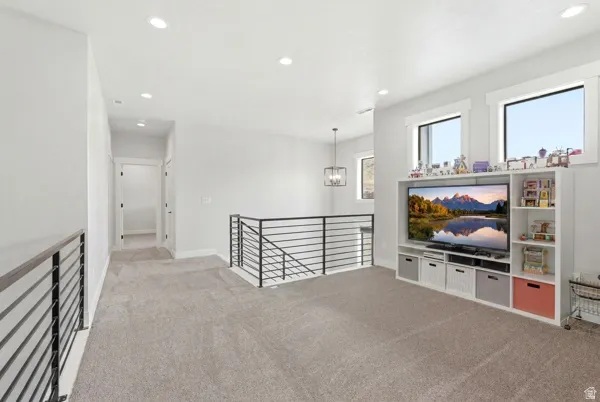 Upper-level space featuring light gray carpeting, recessed ceiling lighting, and a contemporary black metal railing