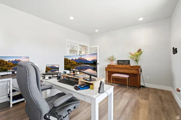 Spacious room featuring wood-finish flooring, recessed lighting, and light-colored walls