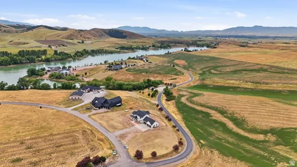 Scenic land parcels featuring a winding paved road, established residences, and distant water frontage
