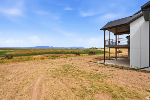 Exterior residence featuring a covered upper-level deck with horizontal metal railings, and a covered lower-level patio