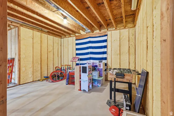 Unfinished basement space featuring exposed wood joists and spray foam insulation on perimeter walls