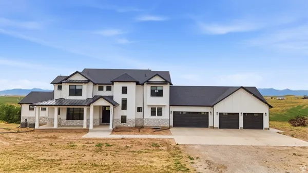 Modern farmhouse exterior featuring white vertical siding, black-framed windows, and a black shingle roof