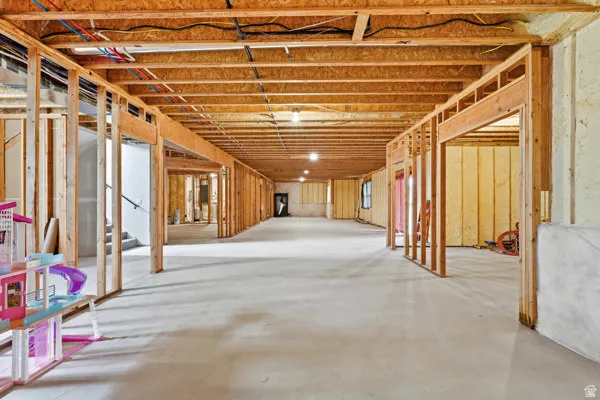 Unfinished lower level featuring exposed wood framing, concrete flooring, and visible electrical and plumbing infrastructure